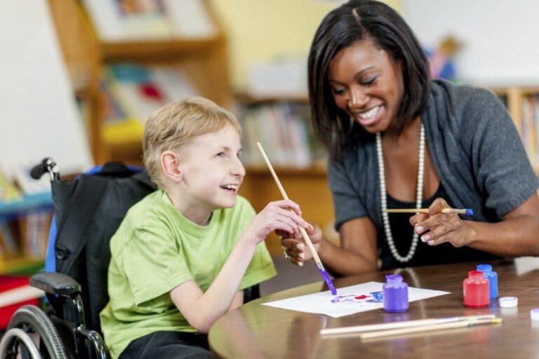 Woman helping child with disability do painting